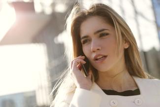 Woman listens to message on cell phone.