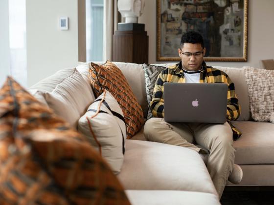 Student working on laptop while sitting on couch